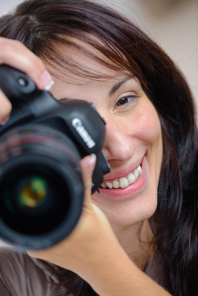cheerful photographer holding dslr camera - Foto, afbeelding
