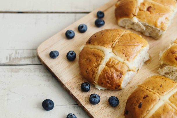 Hot cross buns served on a wooden board with bluberries. Easter food - Foto, Bild