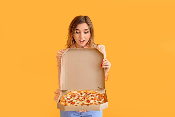 Portrait of surprised young woman with tasty pizza on color background - Photo, Image