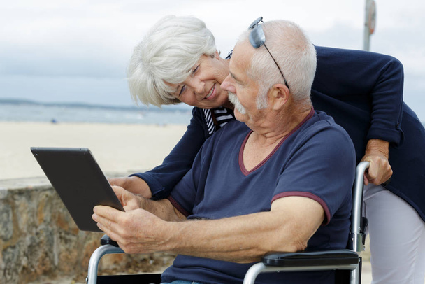 an old couple is using a tablet outdoors - Foto, afbeelding