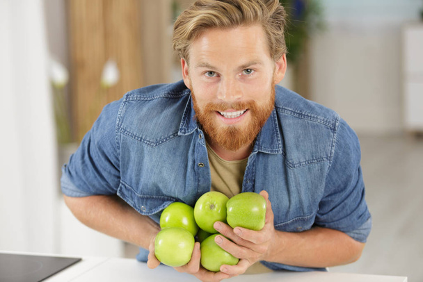 man dropping an armful of apples on to the worktop - Φωτογραφία, εικόνα