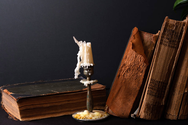Montón de libros antiguos con páginas amarillentas y candelabro de bronce con vela
 - Foto, Imagen