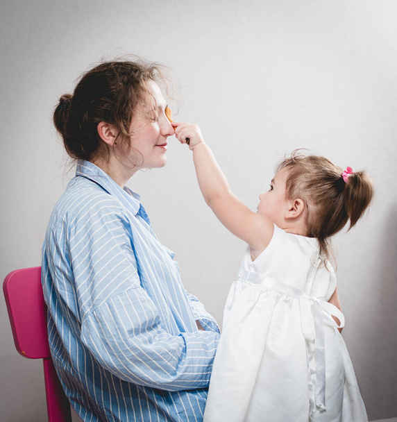 little girl does makeup to her mom - Foto, Imagen