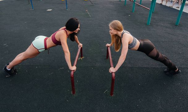 Athletic, sexy girls do push-UPS outdoors. Fitness, healthy lifestyle - Photo, Image