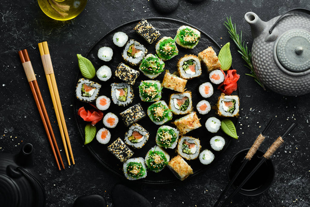 Set of traditional sushi on a black plate. Sushi and rolls on a dark background. - Zdjęcie, obraz