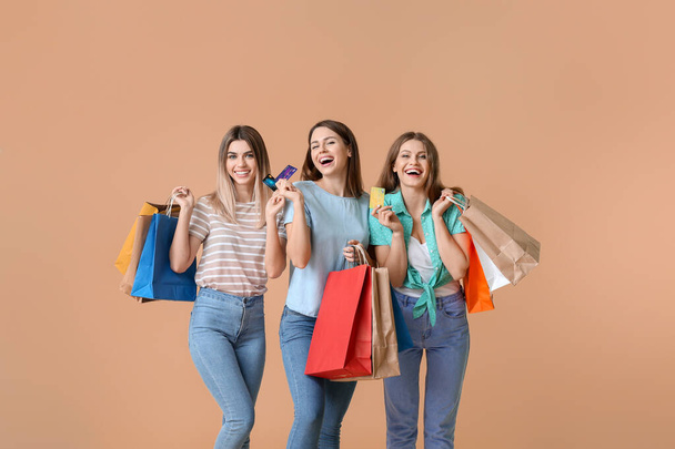 Young women with credit cards and shopping bags on color background - Zdjęcie, obraz