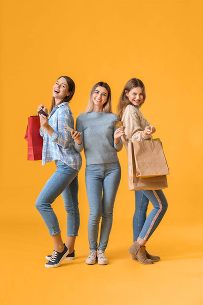 Young women with mobile phone and shopping bags on color background - Foto, afbeelding