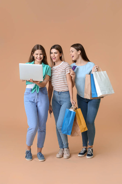 Young women with laptop and shopping bags on color background - Zdjęcie, obraz