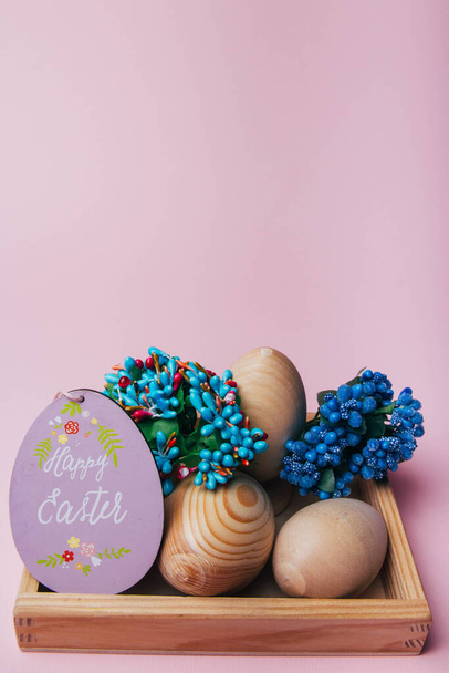 Pascua, huevos de madera, pysanka, cosecha, flores y la inscripción en la tarjeta feliz Pascua.flores azules
 - Foto, Imagen