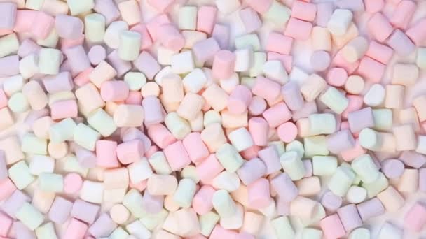 Vista superior de doces de marshmallow em forma de pastel com alguns espalhados na mesa branca pálida
 - Filmagem, Vídeo