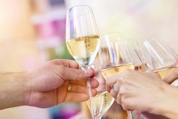 Zbliżenie szczegółów mężczyzn i kobiet ręce brzęczące kieliszki białego szampana lub prosecco na imprezie lub uroczystości na świeżym powietrzu. Ludzie bawiący się pić alkohol toasting okrzyki w kawiarni restauracji. - Zdjęcie, obraz