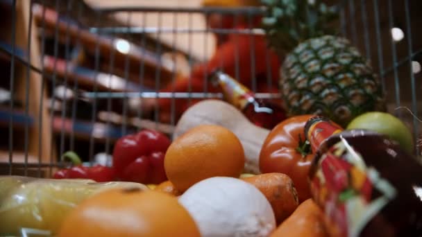 grocery basket - cart full of healthy food and bottles of wine with a man in the background - Materiał filmowy, wideo