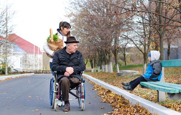 Homem com deficiência e seu cuidador conversam com um menino
 - Foto, Imagem