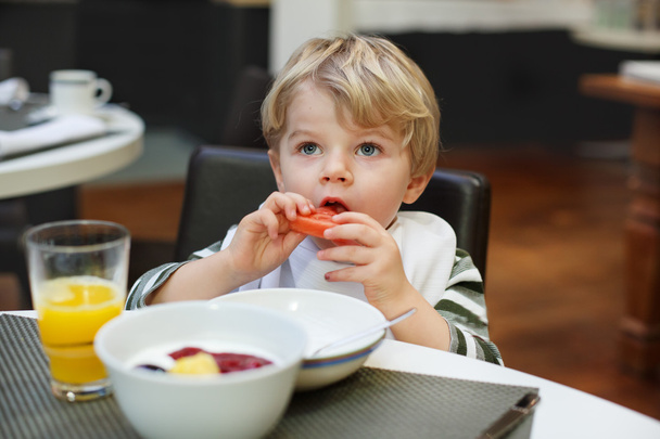 Vaalea pieni poika syö ranskalaisia perunoita ulkona ravintolassa
 - Valokuva, kuva