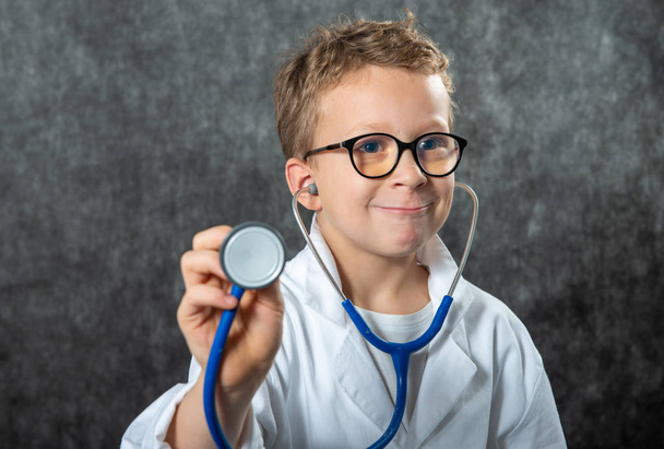 Leuke jongen draagt medisch uniform spelen arts, een portret - Foto, afbeelding