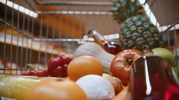 grocery basket - man is putting bread in a trolley full of fruits, vegetables and drinks - Materiał filmowy, wideo