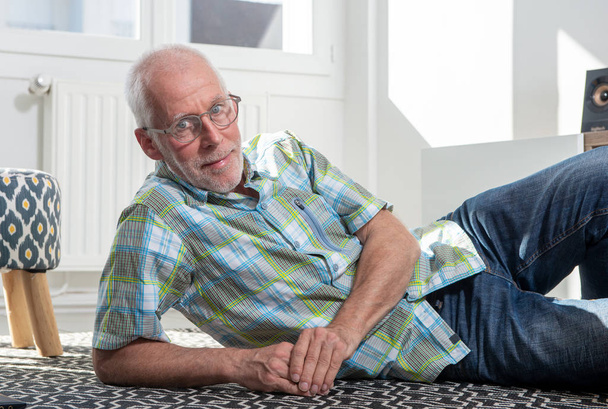 un uomo anziano sdraiato sul pavimento e a riposo
 - Foto, immagini