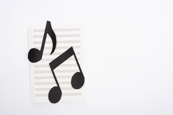 Top view of paper cut notes on music book on white background - Fotoğraf, Görsel