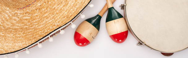 Top view of wooden maracas with tambourine and sombrero on white background, panoramic shot - 写真・画像