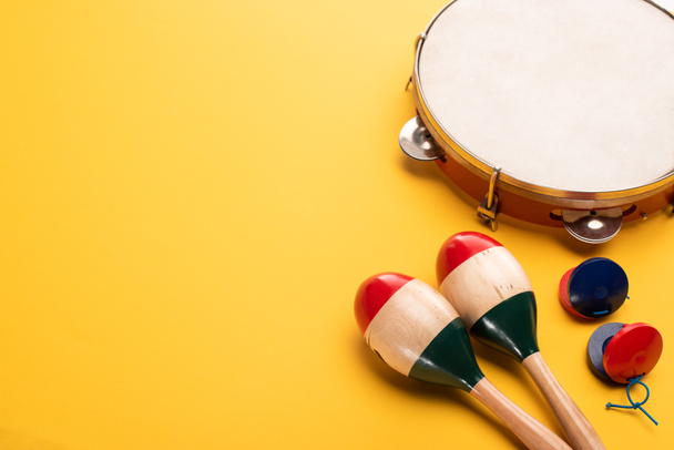 Houten kleurrijke maracas met tamboerijn en castagnetten op gele achtergrond - Foto, afbeelding