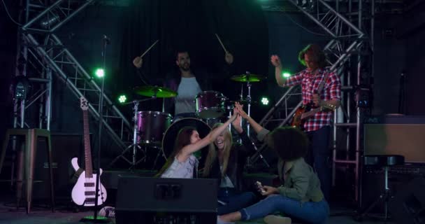 Front view of a group of five multi-ethnic male and female musicians having fun together before performing, cheering, laughing and high fiving each other, in slow motion - Metraje, vídeo