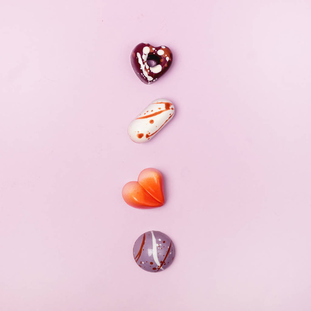 Pembe arka planda farklı renklerle boyanmış lüks bonbonlar Güzel ve özel el yapımı çikolatalı şekerlemeler - Fotoğraf, Görsel