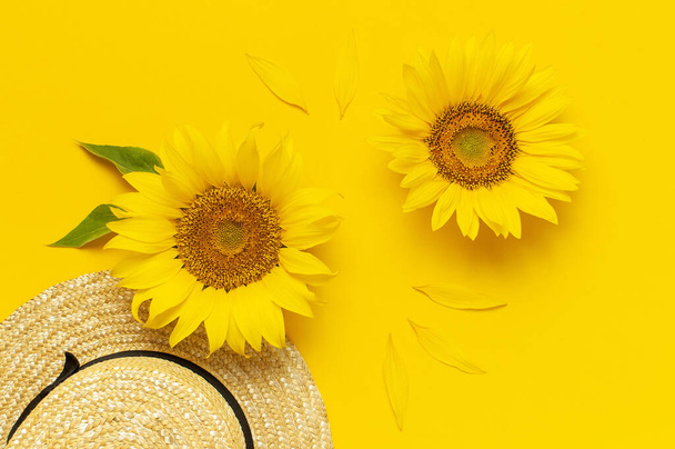 Beautiful fresh sunflowers, straw hat on bright yellow background. Flat lay top view copy space. Autumn or summer Concept, harvest time, agriculture. Sunflower natural background. Flower card. - Photo, Image