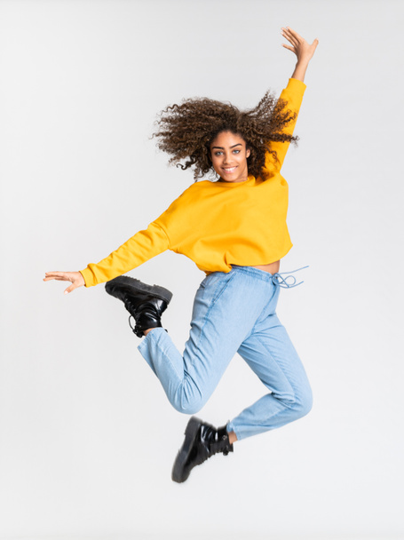 Young African American woman dancing over isolated white background - 写真・画像