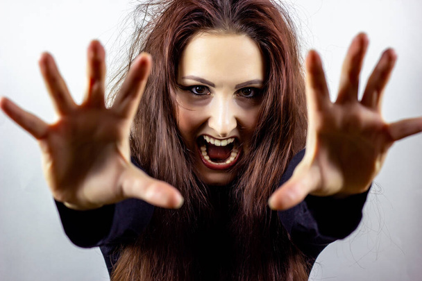 Angry, stressed, frightened and screaming mad young woman in black against light background - 写真・画像