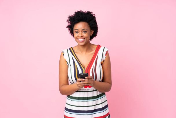 Африканська американка через ізольований рожевий фон відправляє повідомлення з мобільним телефоном - Фото, зображення