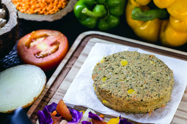 raw vegan burger, before being fried. Thawed meat, with lots of vegetables around. Tomato, sliced onion, peppers, red cabbage - Photo, Image