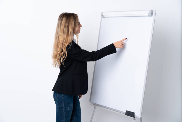 Young woman over isolated white background giving a presentation on white board - Photo, Image