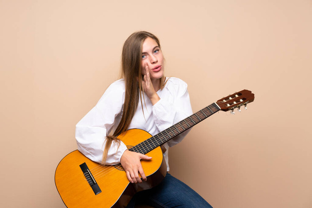 Дівчина-підліток з гітарою над ізольованим фоном щось шепоче
 - Фото, зображення
