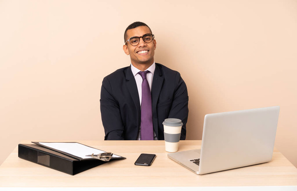 Young business man in his office with a laptop and other documents laughing - Foto, Imagem