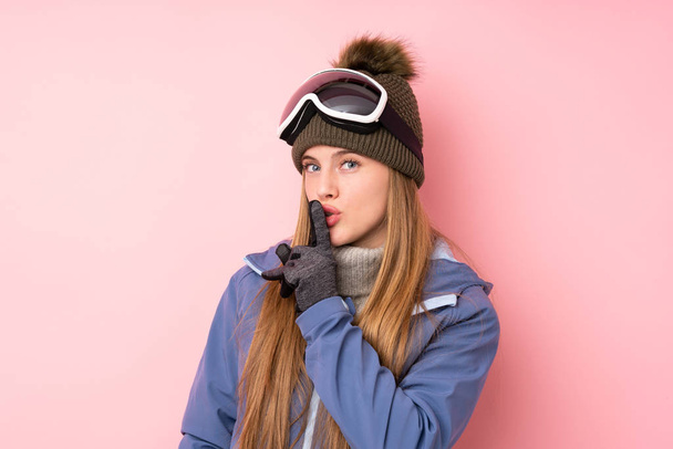 Skier teenager girl with snowboarding glasses over isolated pink background doing silence gesture - Foto, Imagen