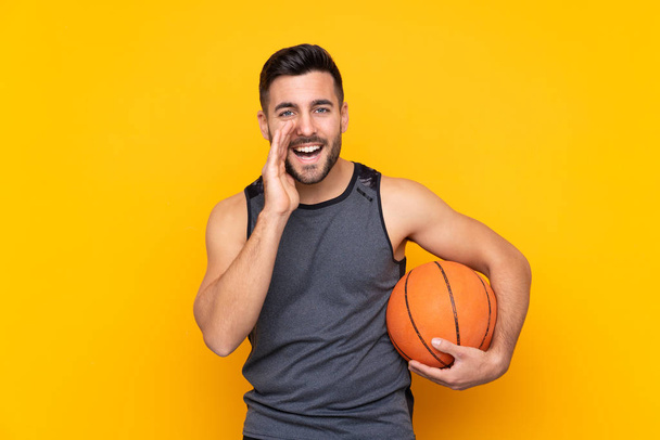 Guapo joven jugador de baloncesto hombre sobre aislada pared blanca gritando con la boca abierta
 - Foto, imagen