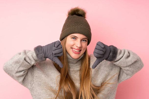 Fiatal tizenéves lány téli kalap felett elszigetelt rózsaszín háttér büszke és önelégült - Fotó, kép