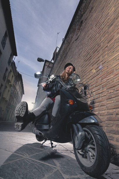 都会的なスタイルでバイクに乗る美しい反抗的な女の子 - 写真・画像