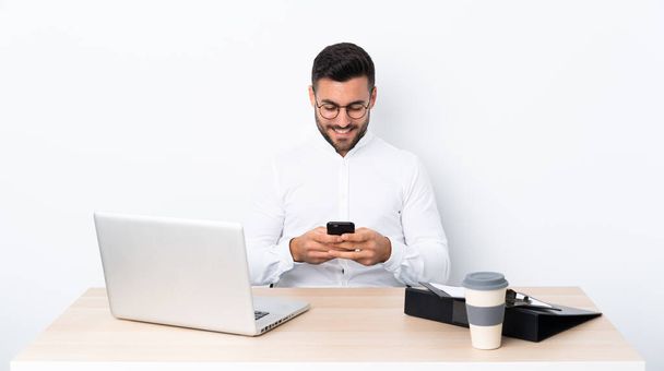 Mladý podnikatel na pracovišti posílá zprávu s mobilním telefonem - Fotografie, Obrázek