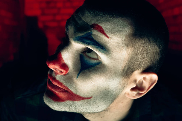 Retrato de cerca de un hombre bromista. Stock foto maquillaje joker en una sala de terror
. - Foto, Imagen