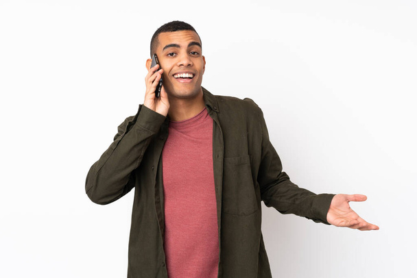 Jeune homme afro-américain sur fond blanc isolé gardant une conversation avec le téléphone portable avec quelqu'un - Photo, image