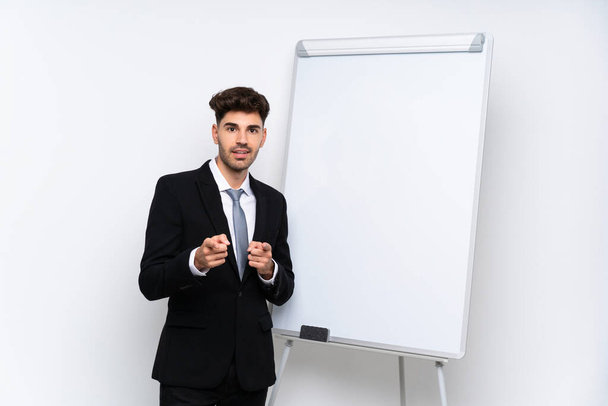 Νεαρός επιχειρηματίας δίνει μια παρουσίαση σε λευκό πίνακα δείχνει το δάχτυλό σας με αυτοπεποίθηση έκφραση - Φωτογραφία, εικόνα