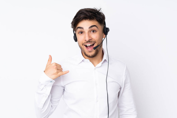 Uomo arabo telemarketer che lavora con un auricolare isolato su sfondo bianco facendo gesto telefonico
 - Foto, immagini