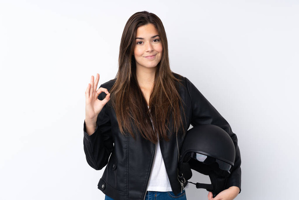 Mujer joven con un casco de motocicleta sobre fondo blanco aislado que muestra un signo de ok con los dedos
 - Foto, Imagen