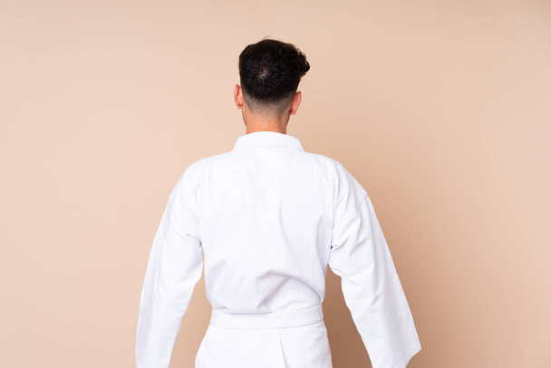 Young man over isolated background doing karate in back position - Photo, image