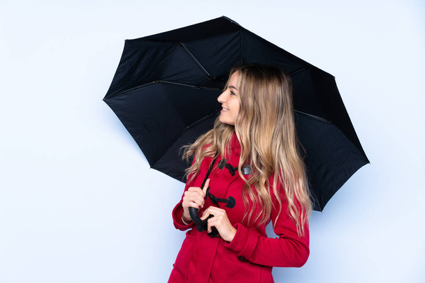 Молода жінка з зимовим пальто і тримає парасольку з щасливим виразом
 - Фото, зображення