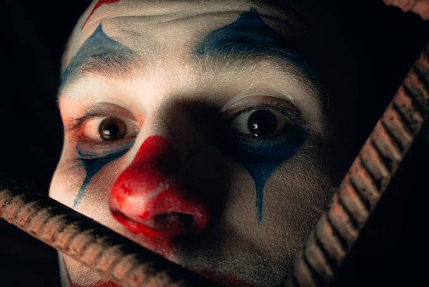 Um retrato de perto de um homem brincalhão. Foto stock joker maquiagem em uma sala de horror
. - Foto, Imagem