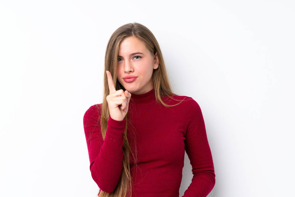 Adolescente loira sobre isolado fundo branco frustrado e apontando para a frente
 - Foto, Imagem