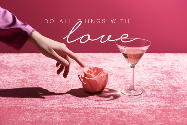 περικοπή άποψη της γυναίκας αγγίζοντας τριαντάφυλλο κοντά σε γυαλί με ποτό σε βελούδινο ύφασμα που απομονώνονται σε ροζ, κάνει όλα τα πράγματα με την εικόνα αγάπη - Φωτογραφία, εικόνα