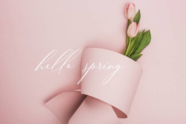 top view of tulips wrapped in paper on pink background, hello spring illustration - Foto, Imagen